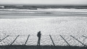 Long shadow of a woman on a beach at golden hour, Camino de Santiago coastline