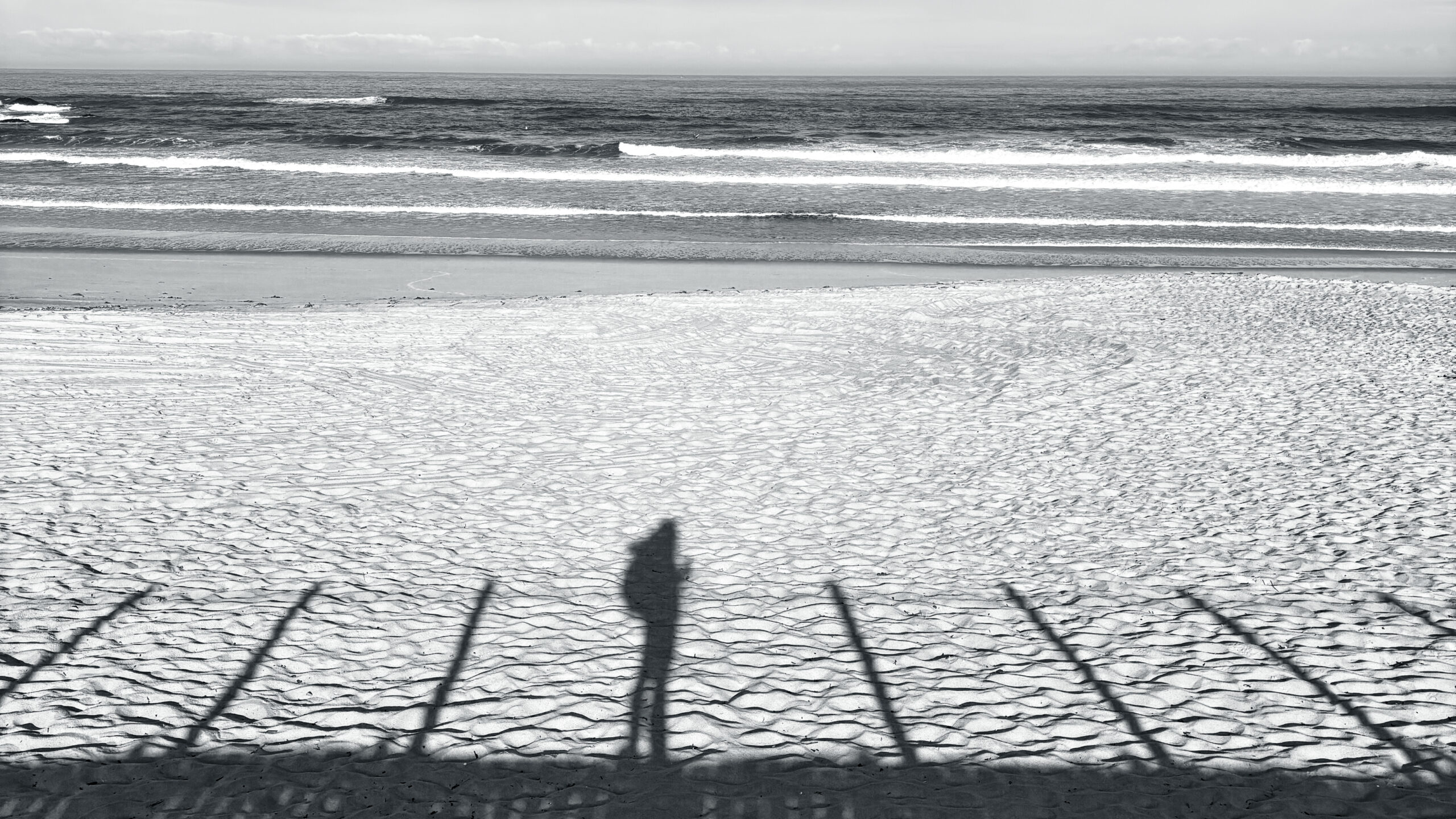 Long shadow of a woman on a beach at golden hour, Camino de Santiago coastline