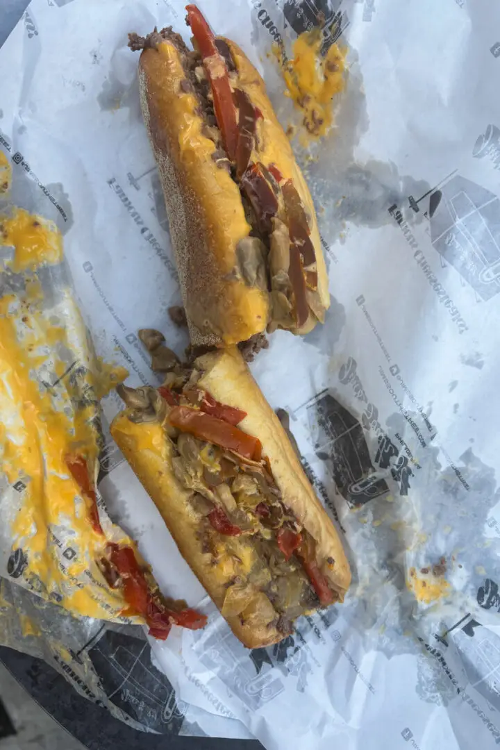 A Philadelphia cheesesteak from Jim's South St with cheese, peppers, and onions, on its paper wrapping.